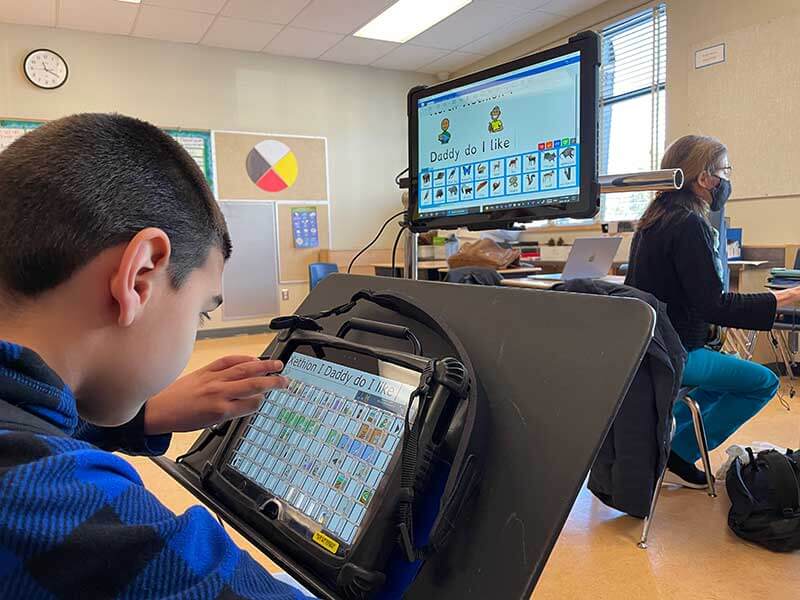 A student playing on his communication device that is connected to a screen